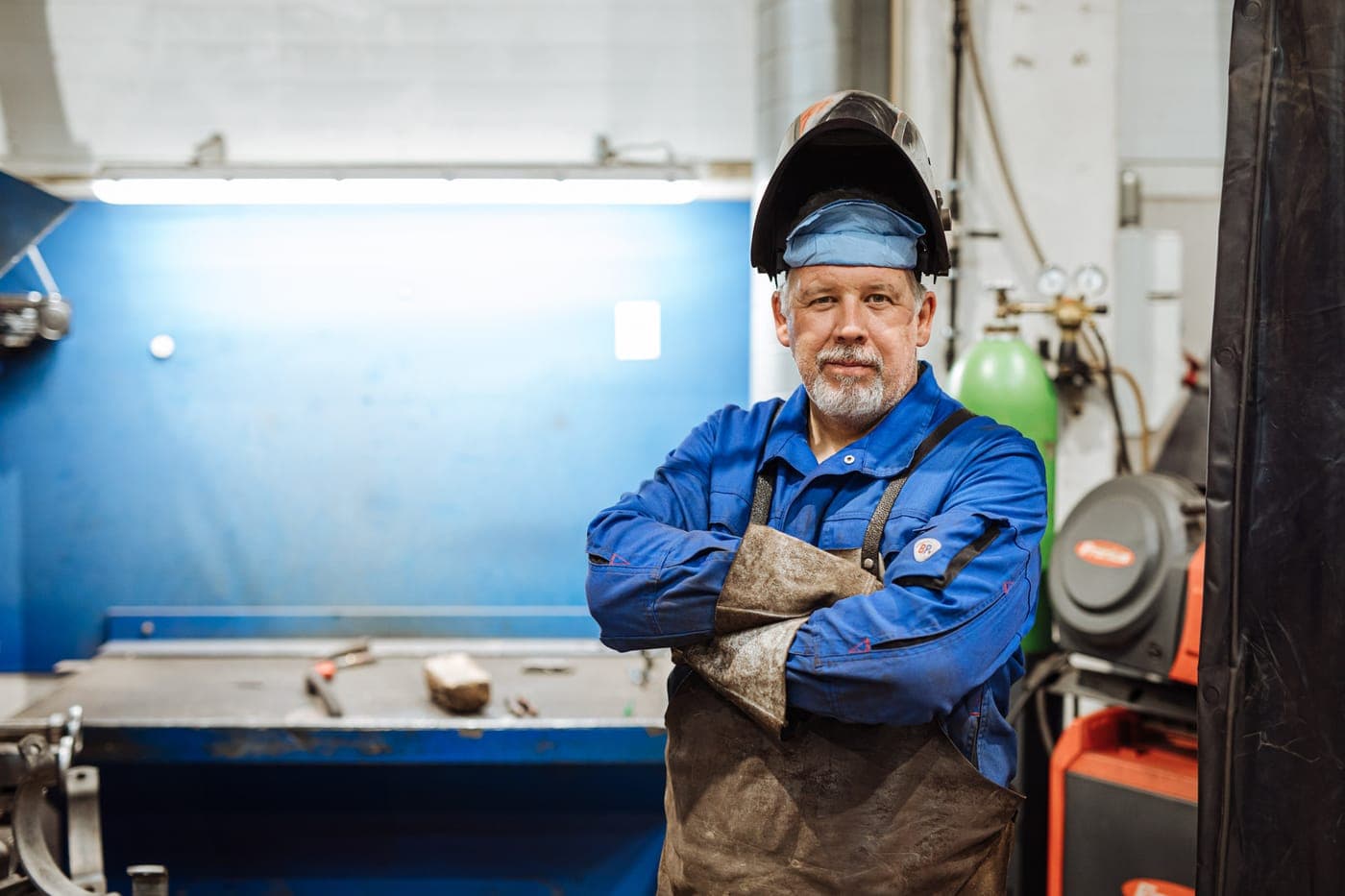 Schweißer mit hochgeklapptem Helm in der Hammerschmid-Werkstatt